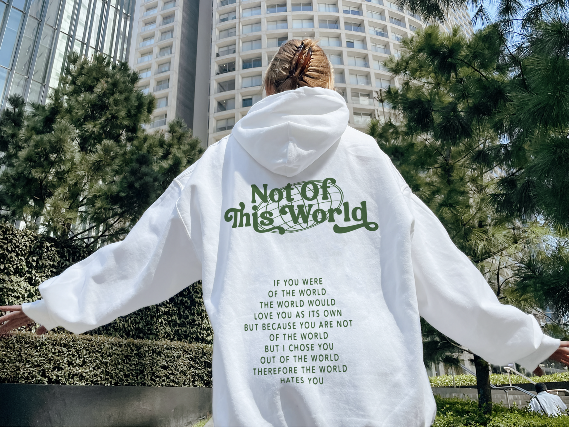 Person wearing a white hoodie with text in an urban setting